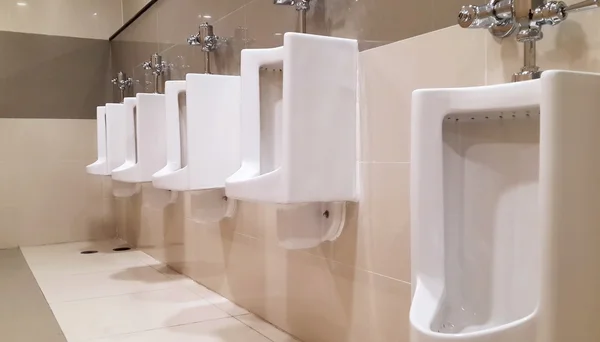 Eine Reihe von Urinalen in einer gefliesten Wand in einer öffentlichen Toilette — Stockfoto