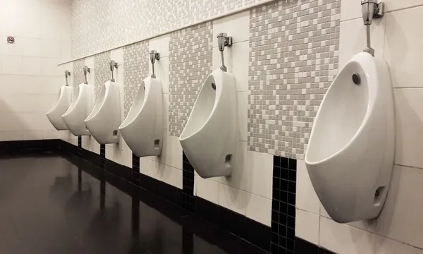 Een rij van urinoirs in betegelde muur in een publiek toilet — Stockfoto