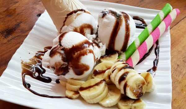 Кокосове морозиво з бананом в білій тарілці на дерев'яному столі — стокове фото