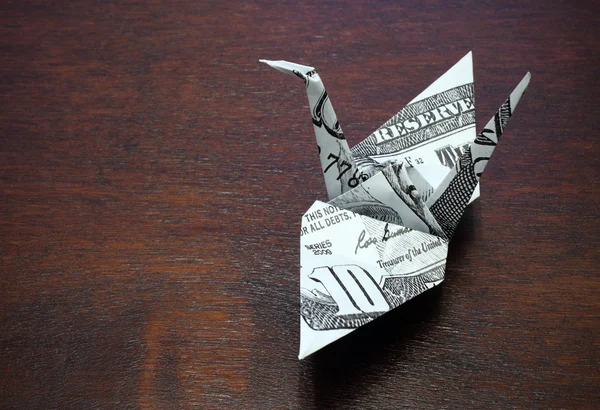 Origami crane from a money note on wood table — Stock Photo, Image