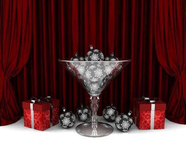 Glass cup with New Year decorative balls with red presents in front of the red drapery — Stock Photo, Image