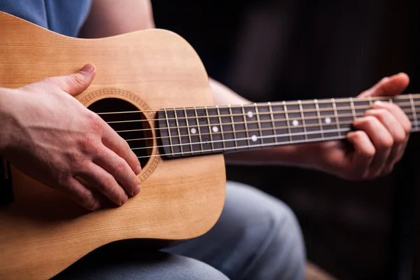 Guitarra marrón en las manos en el tipo que lo toca —  Fotos de Stock
