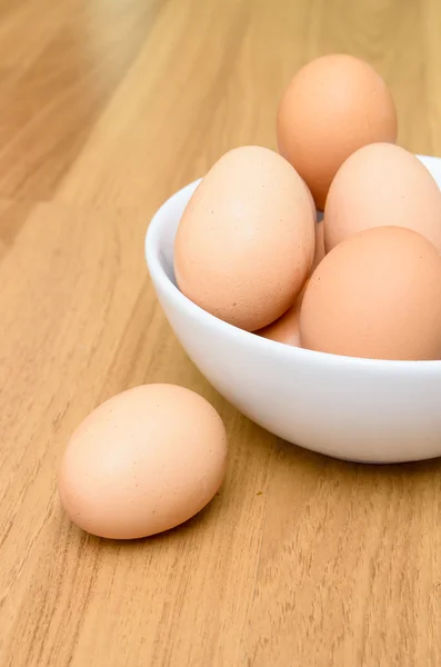 Eier in weißer Schüssel auf Holztisch — Stockfoto