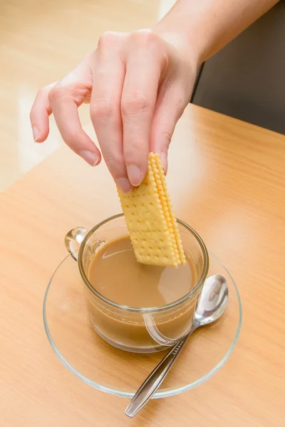 Mulher mergulhando biscoito em café quente na hora da manhã — Fotografia de Stock