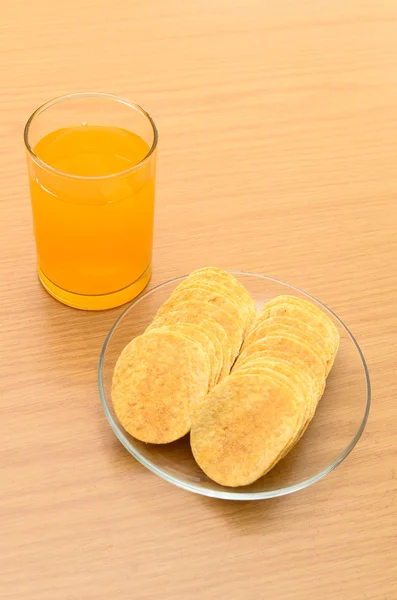 Appelsinjuice og kartoffelchips på træbordet - Stock-foto