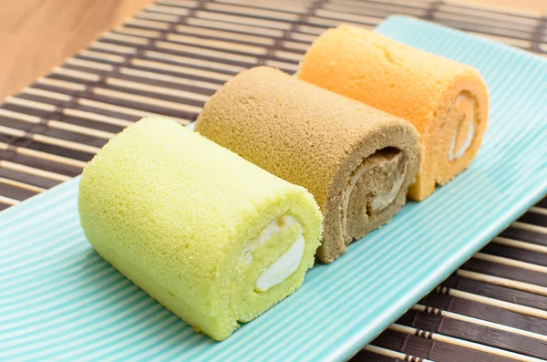 Colorful swiss roll on green dish on bamboo mat — Stock Photo, Image