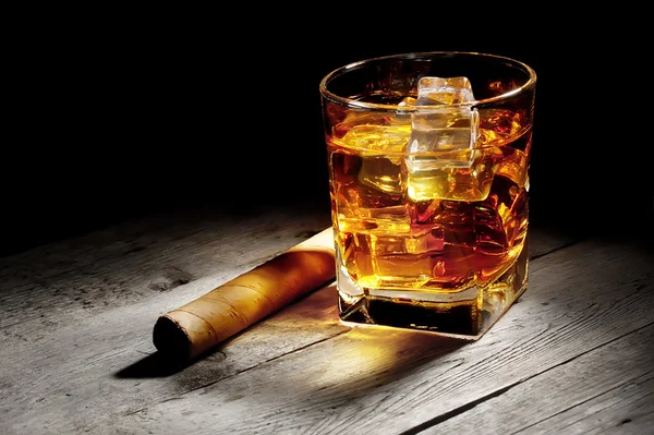 Glas Whisky mit einer Zigarre Stockbild