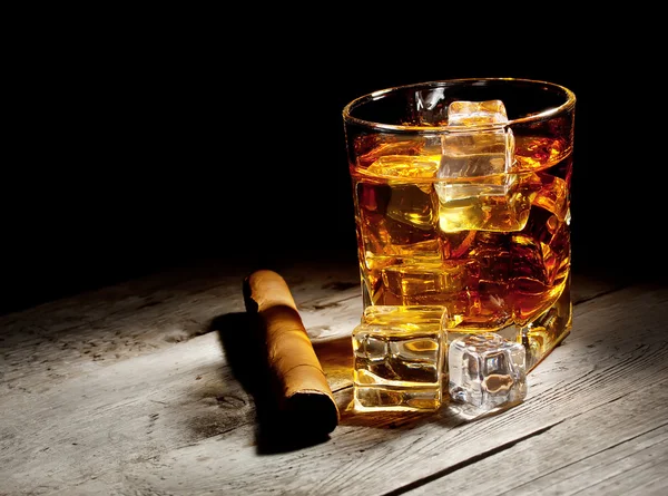 Sklo ve věku whisky s doutníkem a kostky ledu — Stock fotografie