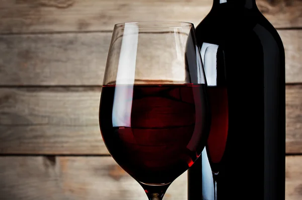 Detalle de una copa de vino tinto con una botella — Foto de Stock