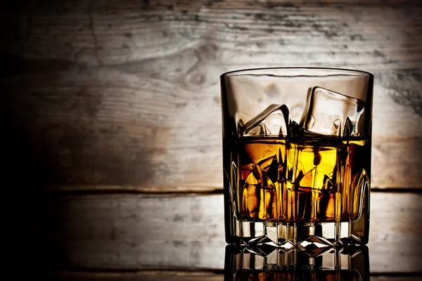 Faceted glass of whiskey with ice — Stock Photo, Image