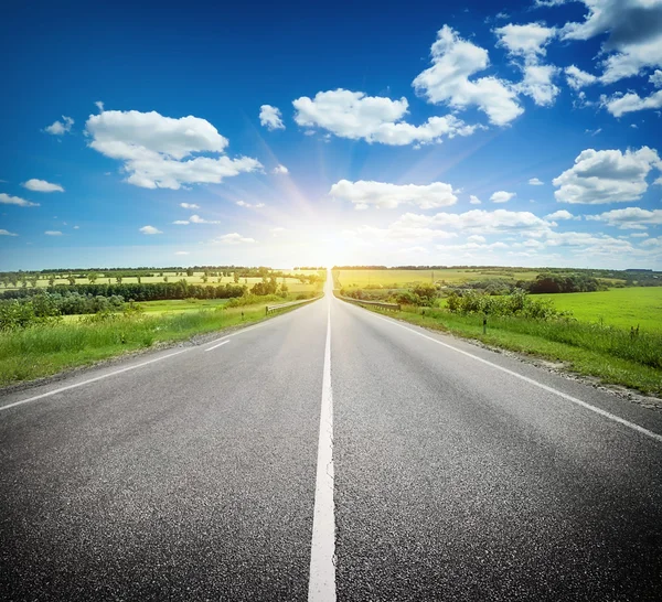 Estrada de asfalto no campo abaixo do céu azul — Fotografia de Stock