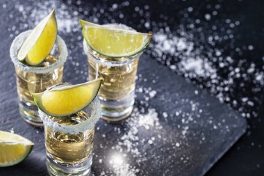 Koyu renkli masada limonlu tekila serpiştirilmiş tuz.