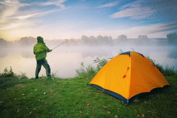 Fischer am See mit orangefarbenem Zelt an nebligem Morgen — Stockfoto