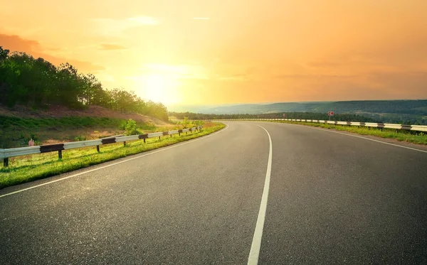 Asphalt Autobahn gegen Sonnenuntergang gelben Himmel — Stockfoto