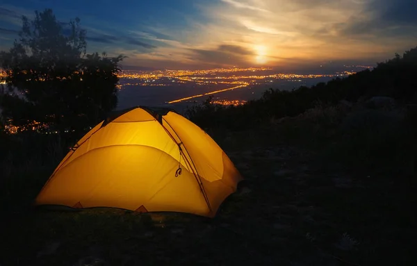 Orange tourist tent against backdrop of city lights at sunset — Stock Photo, Image