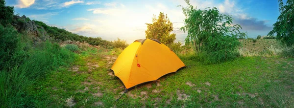 Панорама холма с оранжевой туристической палаткой на вершине — стоковое фото