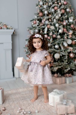 Mutlu kutlamalar. Yeni yılı kutlayan güzel bir kız. Noel ağacının yanında giyinmiş küçük bir kız.. 