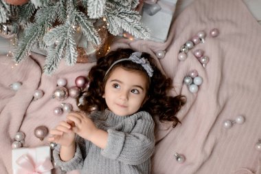 Mutlu kutlamalar. Yeni yılı kutlayan güzel bir kız. Noel ağacının yanında giyinmiş küçük bir kız.. 