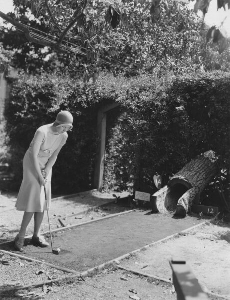 Женщина играет в мини-гольф
