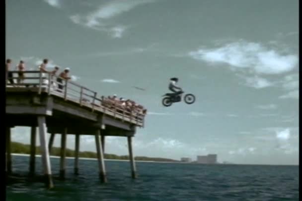 Stuntman guida moto fuori molo nell'oceano — Video Stock