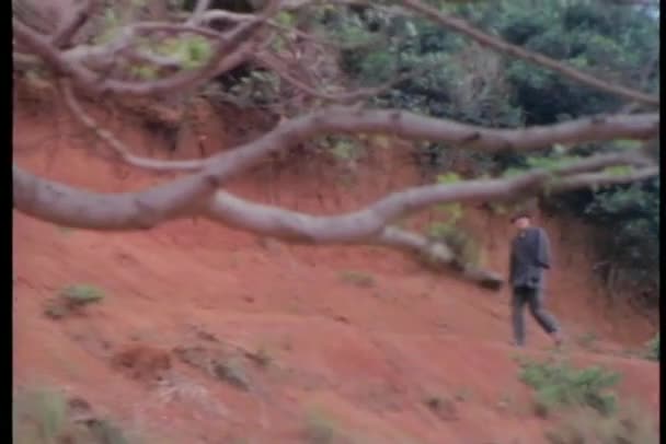 Zoom arrière homme marchant à travers chemin de colline — Video