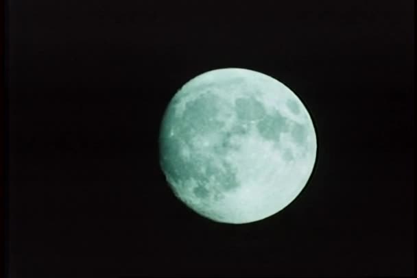 Wide shot van bijna volle maan tegen zwarte lucht — Stockvideo