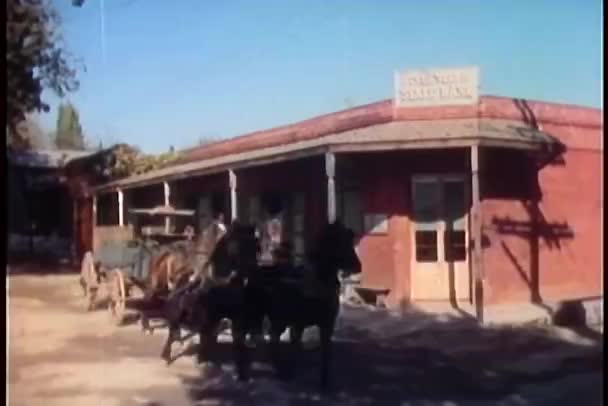 Человек, выбегающий из банка и стреляющий в сбежавшую лошадиную карету — стоковое видео