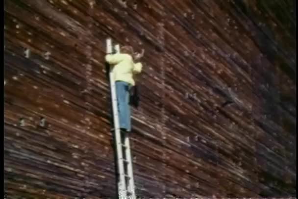 Man on a stepladder hammering into wall — Stock Video