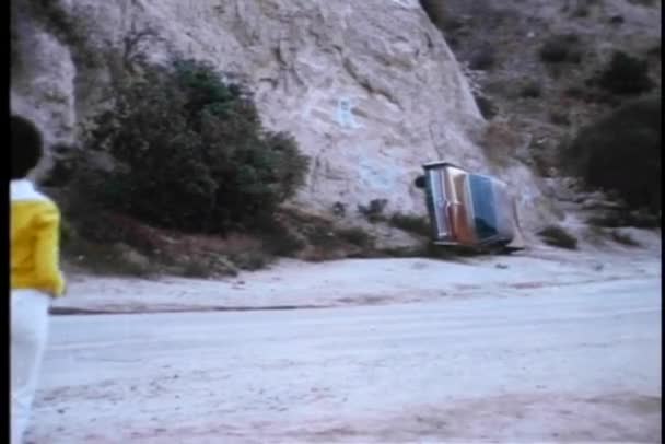 Femme courant vers une voiture renversée sur une route de montagne — Video