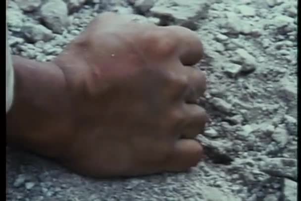 Крупный план сжатого кулака, поднимающего гравий — стоковое видео