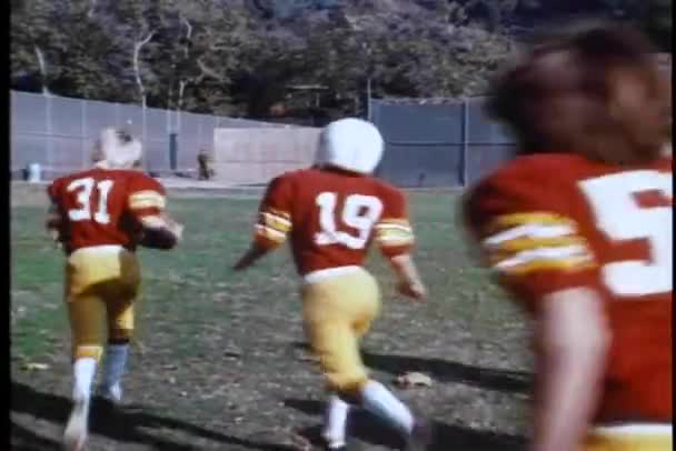 High school football team and coach running across field — Stock Video