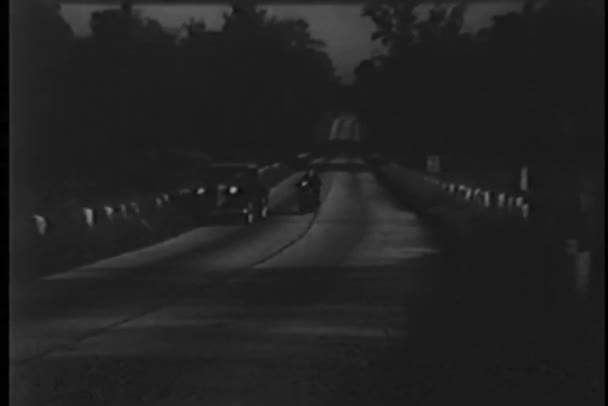 Поліцейський на мотоциклі зупиняє старовинний автомобіль на заміській дорозі вночі — стокове відео