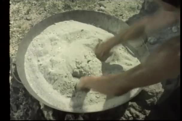 Руки выдерживают боль от нагретого песка в кастрюле — стоковое видео