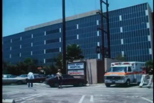 Wide shot of walking in front of hospital — Stock Video