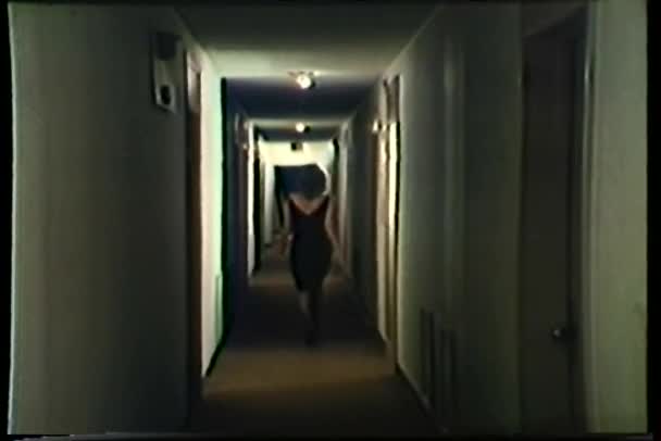 Πίσω όψη γυναίκας στο μαύρο φόρεμα περπάτημα κάτω διάδρομο ξενοδοχείο — Αρχείο Βίντεο