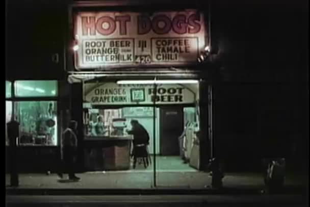 Wide shot of storefront on city street at night — Stock Video
