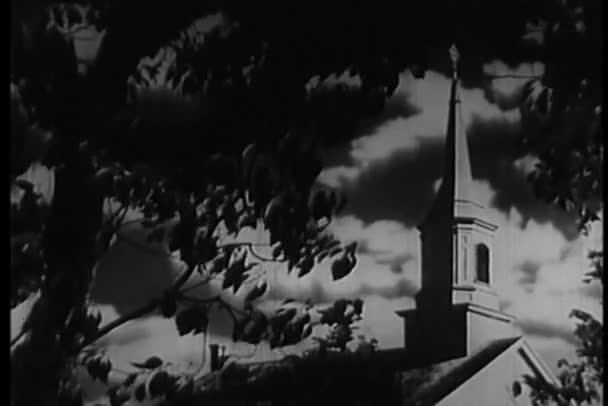 Amplia vista angular del campanario de la iglesia desde detrás del árbol — Vídeos de Stock