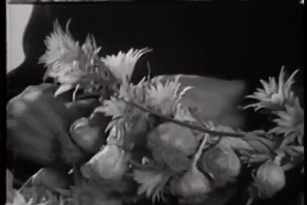 Nahaufnahme von Händen, die Blumen und Knoblauch zu einem Kranz verschränken — Stockvideo