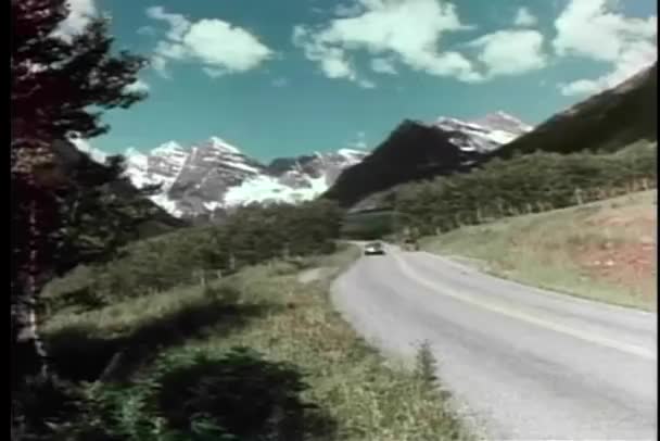 Ретро-машина едет по горной дороге в солнечный день — стоковое видео