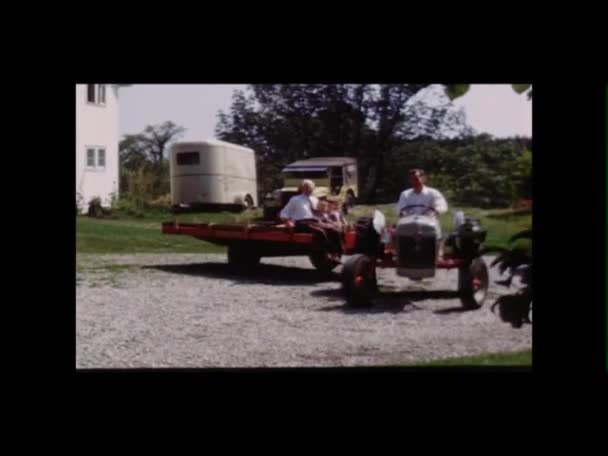Uomo sul trattore che dà alla famiglia un passaggio su un rimorchio a pianale — Video Stock