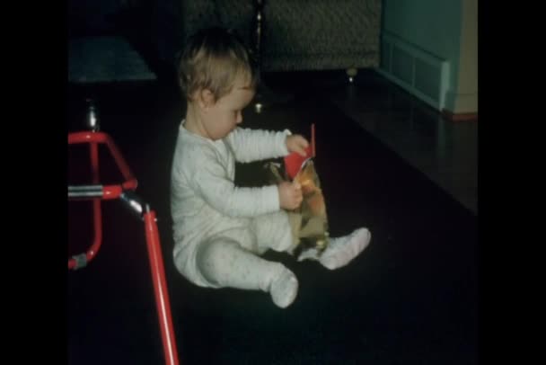 Baby sitting on floor opening gift — Stock Video