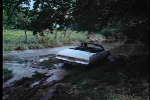 Rear view of man driving convertible through creek — Stock Video