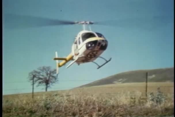 Helicopter equipped with film camera landing in field — Stock Video