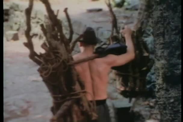 Μεγέθυνση shirtless άνθρωπος, φέρνοντας δέσμες της ραβδιά πάνω από τους ώμους — Αρχείο Βίντεο