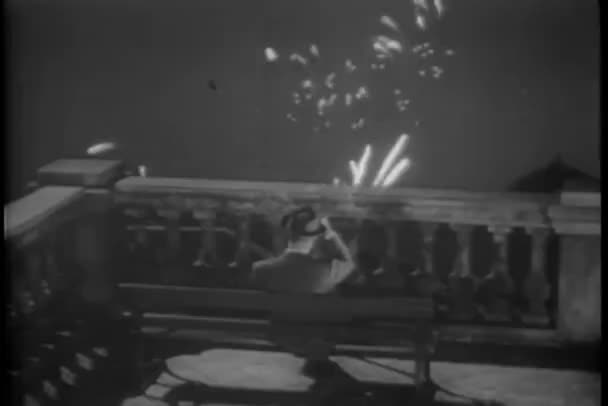 Πίσω όψη του ανθρώπου στον πάγκο, βλέποντας τα πυροτεχνήματα από βεράντα — Αρχείο Βίντεο