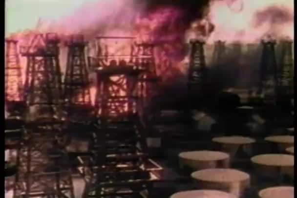 Широкий выстрел черного дыма распространяется через горящий нефтеперерабатывающий завод к резервуарам хранения нефти — стоковое видео