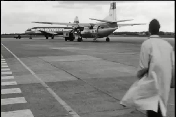 Человек с заднего вида бежит на взлетной полосе к самолету — стоковое видео