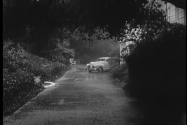 1940s car stopping on side of house in the rain — Stock Video