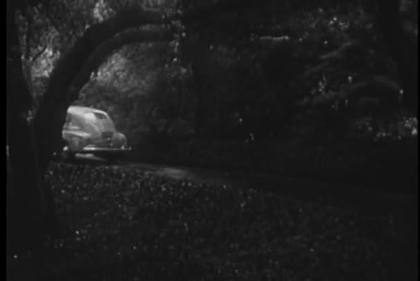 Car driving up road to house in the rain, 1940s — Stock Video