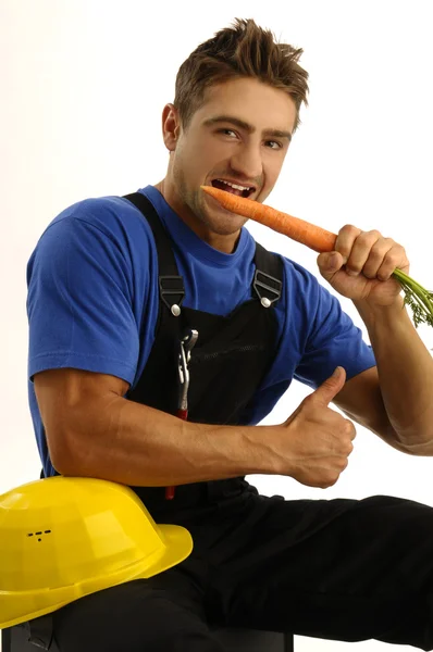 Joven trabajador comiendo zanahoria — Foto de Stock